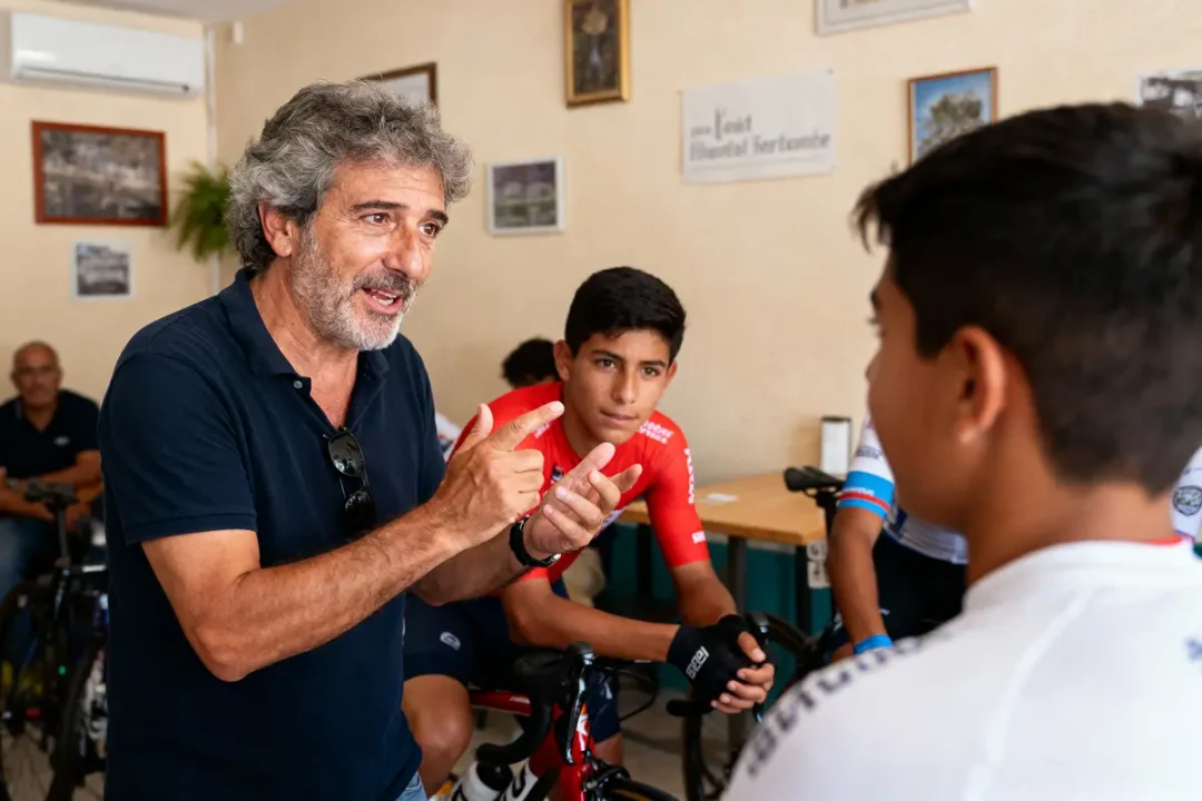 Homme discutant avec jeunes cyclistes en tenue sportive, intérieur, ambiance conviviale et studieuse.