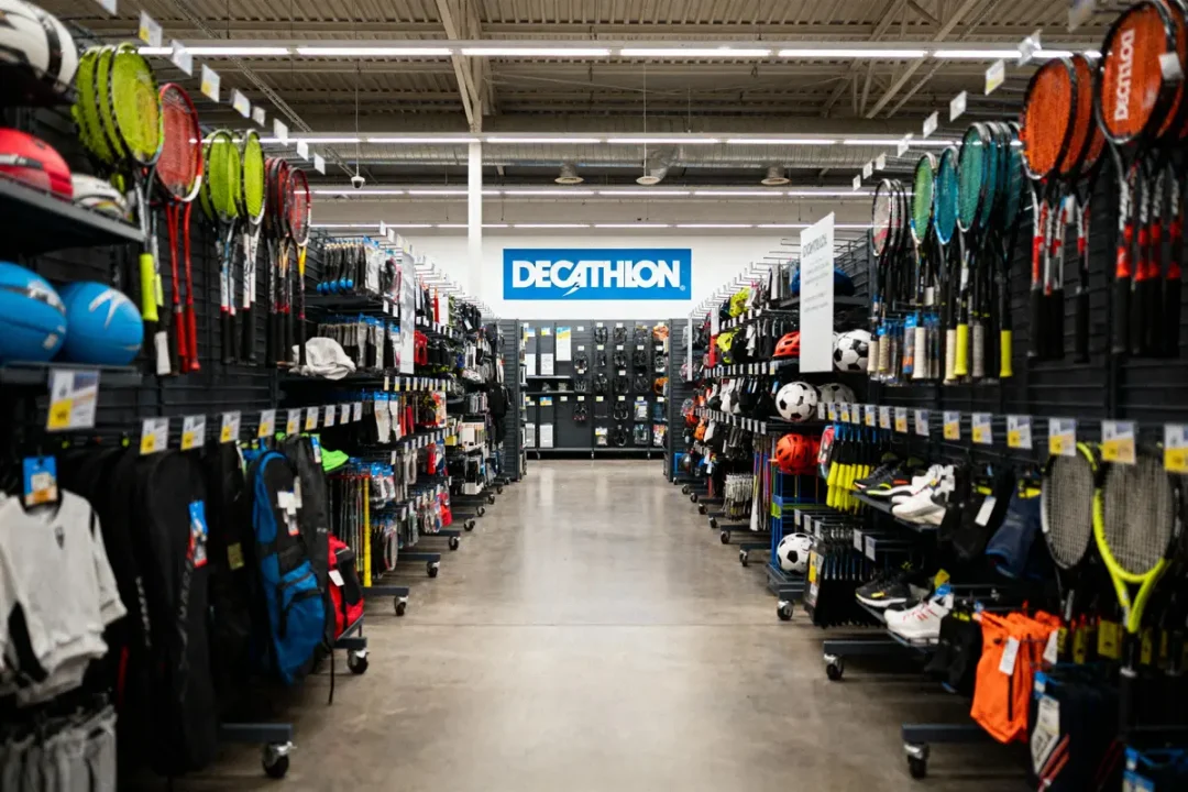 Magasin de sport Decathlon avec équipements de tennis, football, et autres articles sportifs dans les rayons.