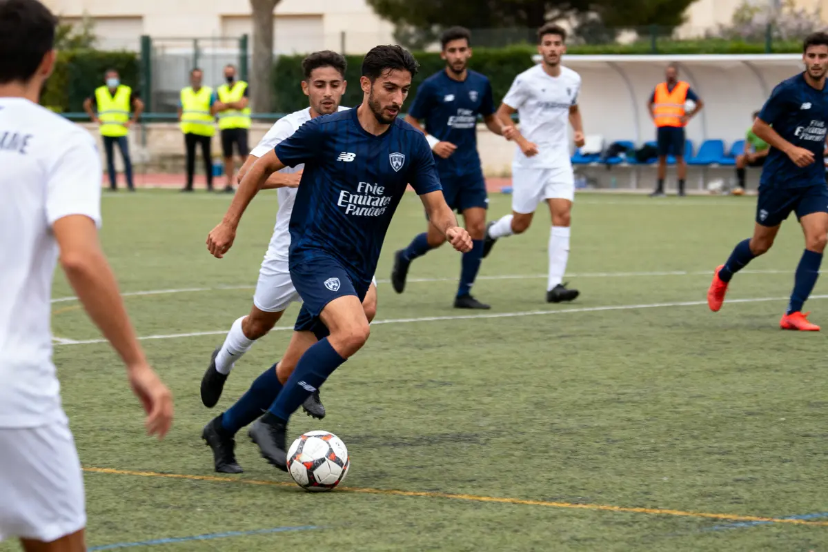 Joueurs de football en match, actions sur le terrain avec ballon, tenues bleues et blanches.