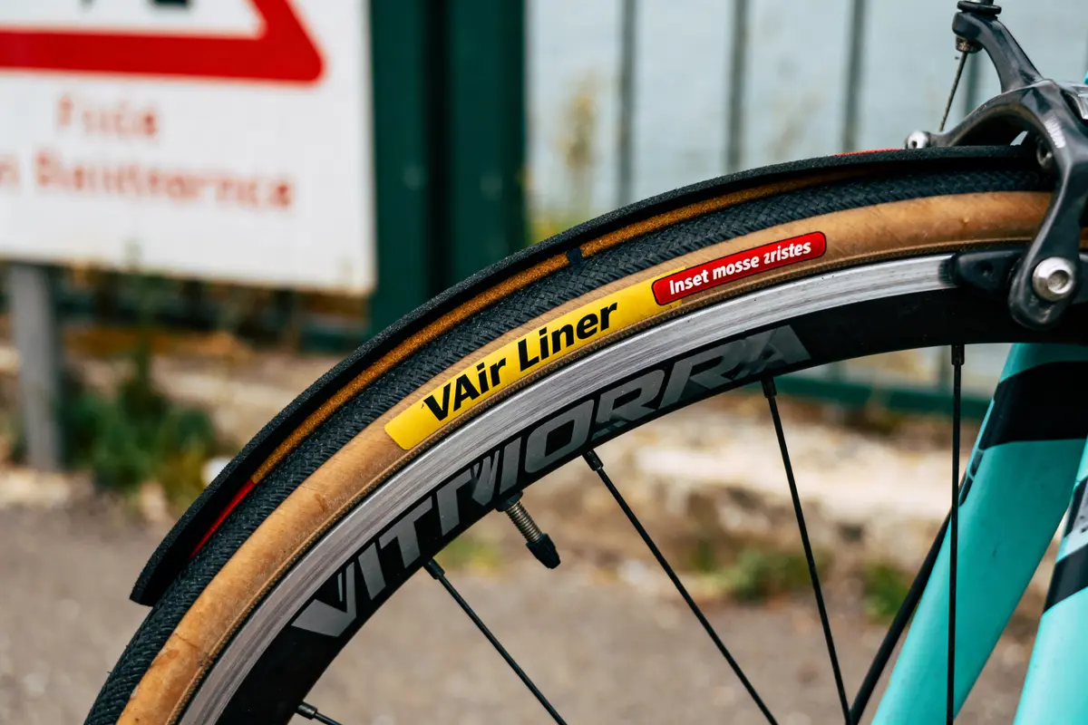 Roue de vélo avec pneu Vittoria, inscription "VAir Liner", cadre bleu en arrière-plan flou.