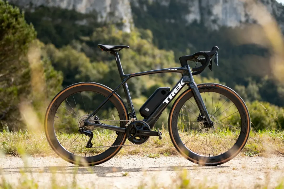 Vélo de course Trek noir sur chemin, paysage naturel en arrière-plan avec montagnes et végétation.