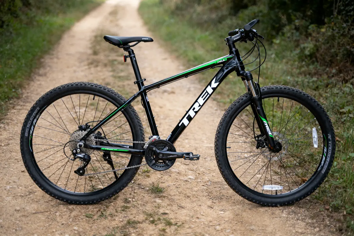 VTT noir et vert sur chemin de terre entouré de végétation.