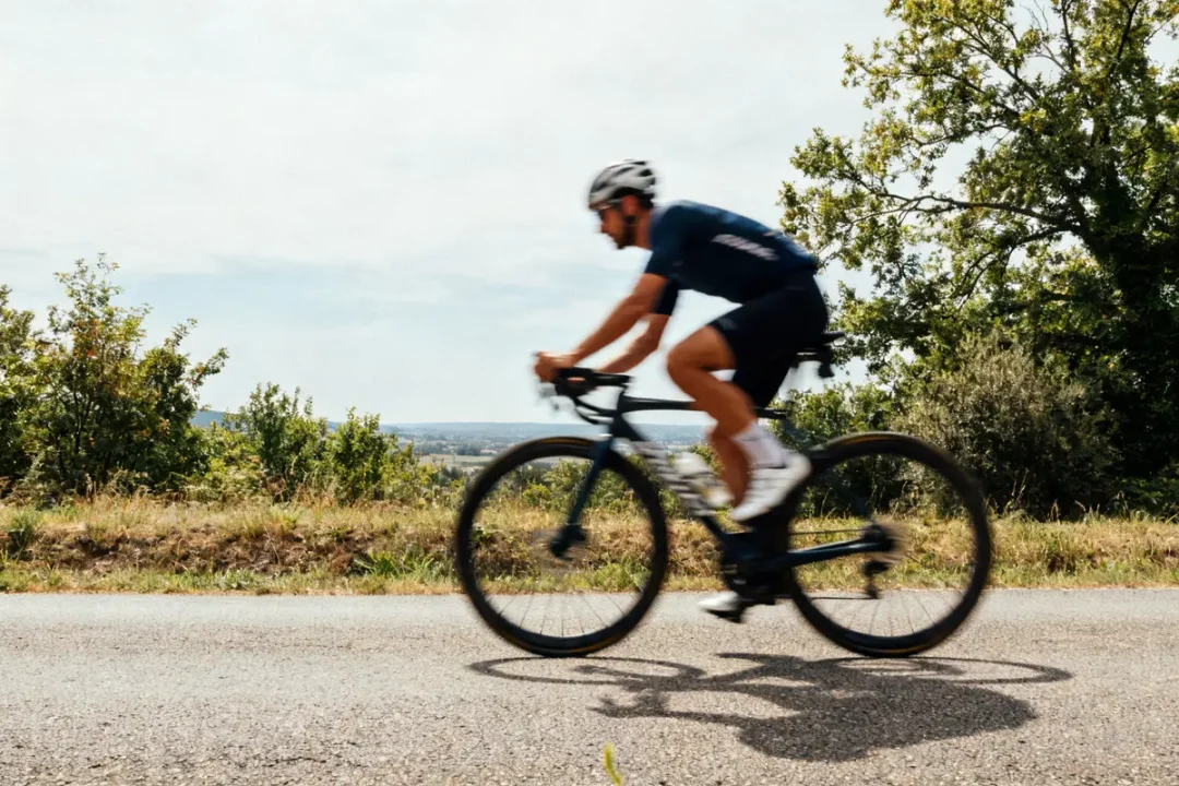 Cycliste solitaire pédalant rapidement sur route campagnarde verdoyante en améliorant son FTP velo