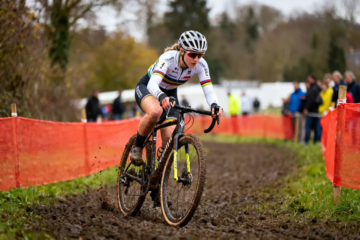 Cycliste Puck Pieterse en action sur un parcours de cyclo-cross boueux en compétition.