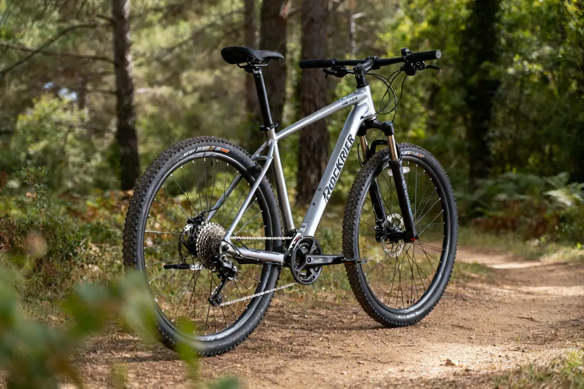 Vélo Rockrider 540 argenté sur chemin forestier en pleine nature.