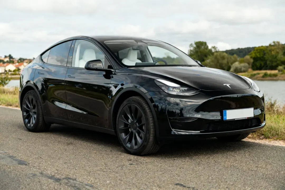 Voiture électrique noire Tesla Model YL garée sur une route de campagne.