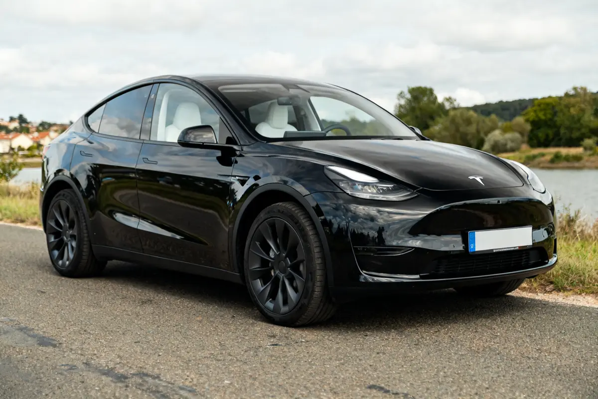 Voiture électrique noire Tesla Model YL garée sur une route de campagne.