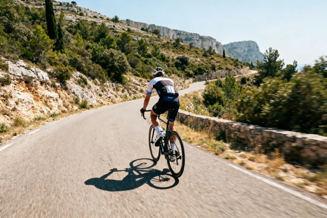 Cycliste sur route montagneuse pendant le Tour de la Provence 2025 sous le soleil.