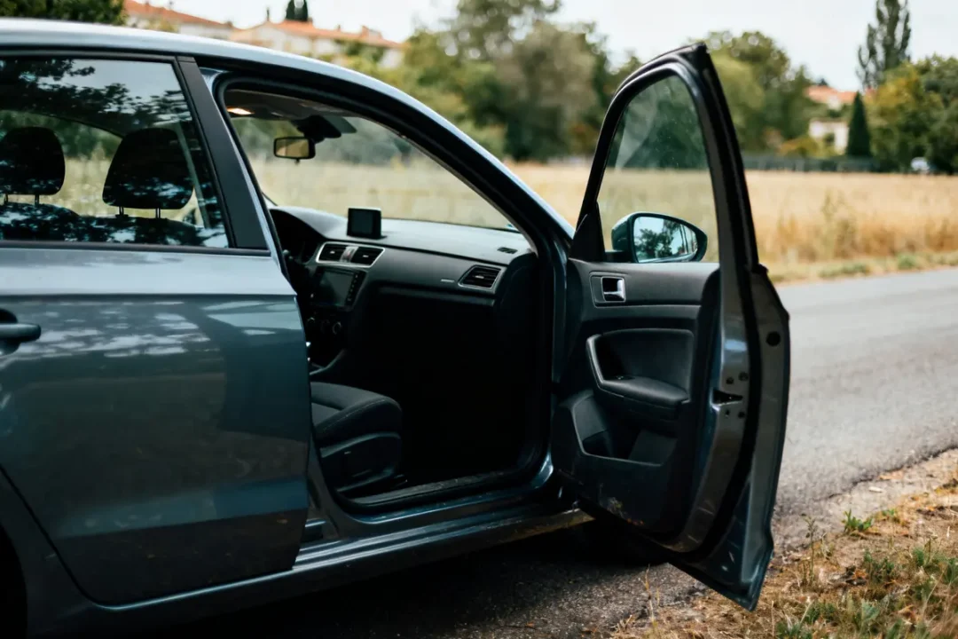 Voiture bleue avec porte ouvert sur une route de campagne tranquille