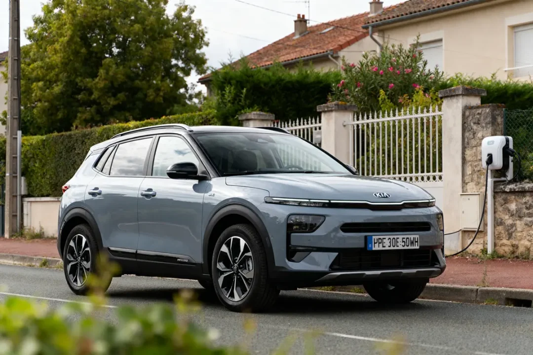 SUV électrique Kia EV5 stationné près d'une borne de recharge en milieu résidentiel