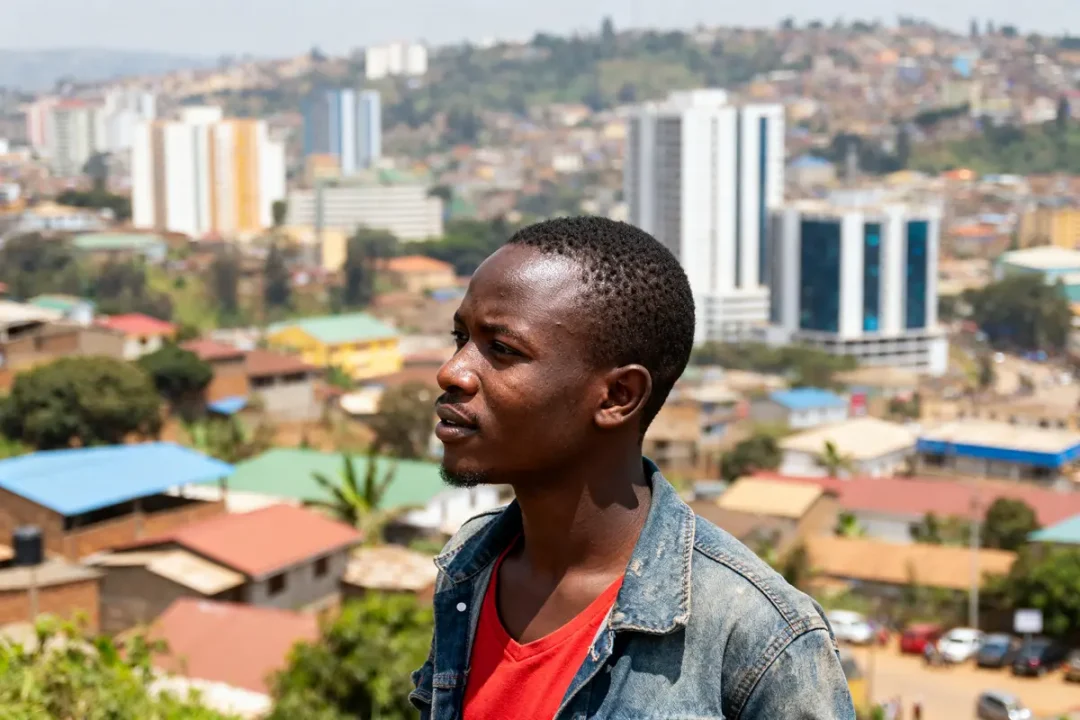 Homme devant panorama urbain de Kigali avec bâtiments modernes en arrière-plan