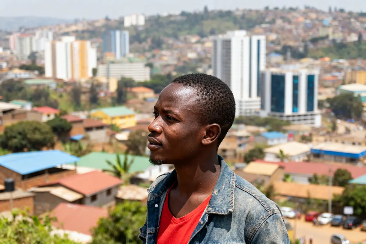 Homme devant panorama urbain de Kigali avec bâtiments modernes en arrière-plan