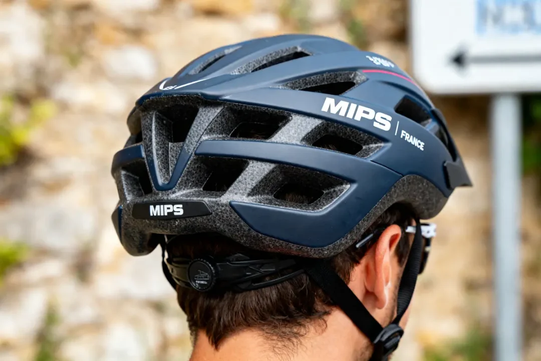 Homme portant un casque MIPS bleu pour cyclisme, vue de dos en extérieur