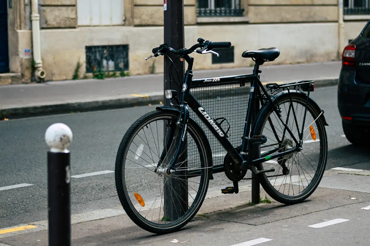 Vélo de ville noir attaché à un poteau d'une marque de vélo connue en France