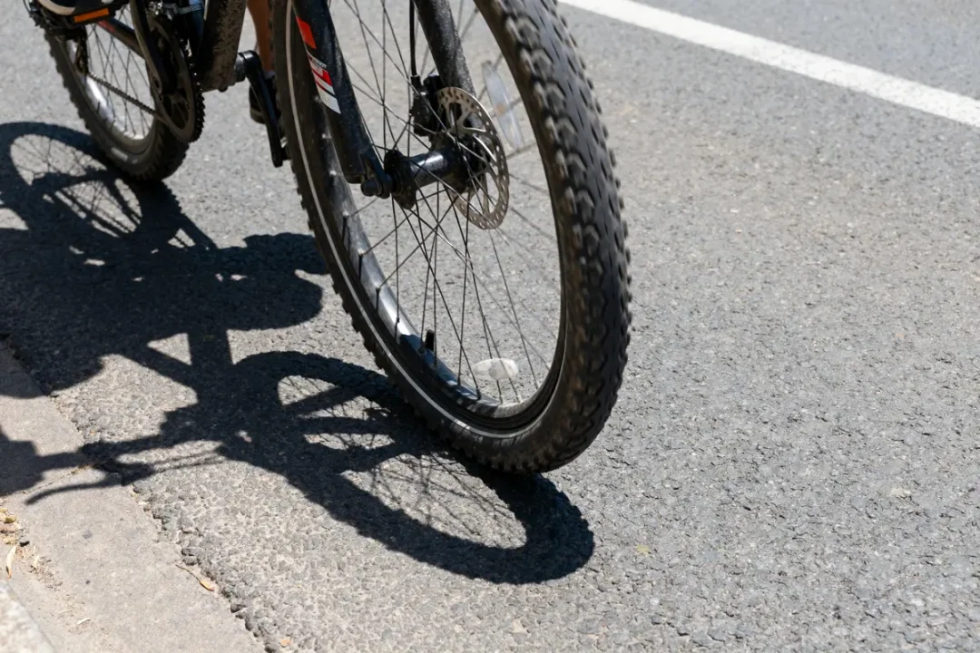 Roue de vélo sur route montrant une roue voilée en mouvement ombrée par le soleil
