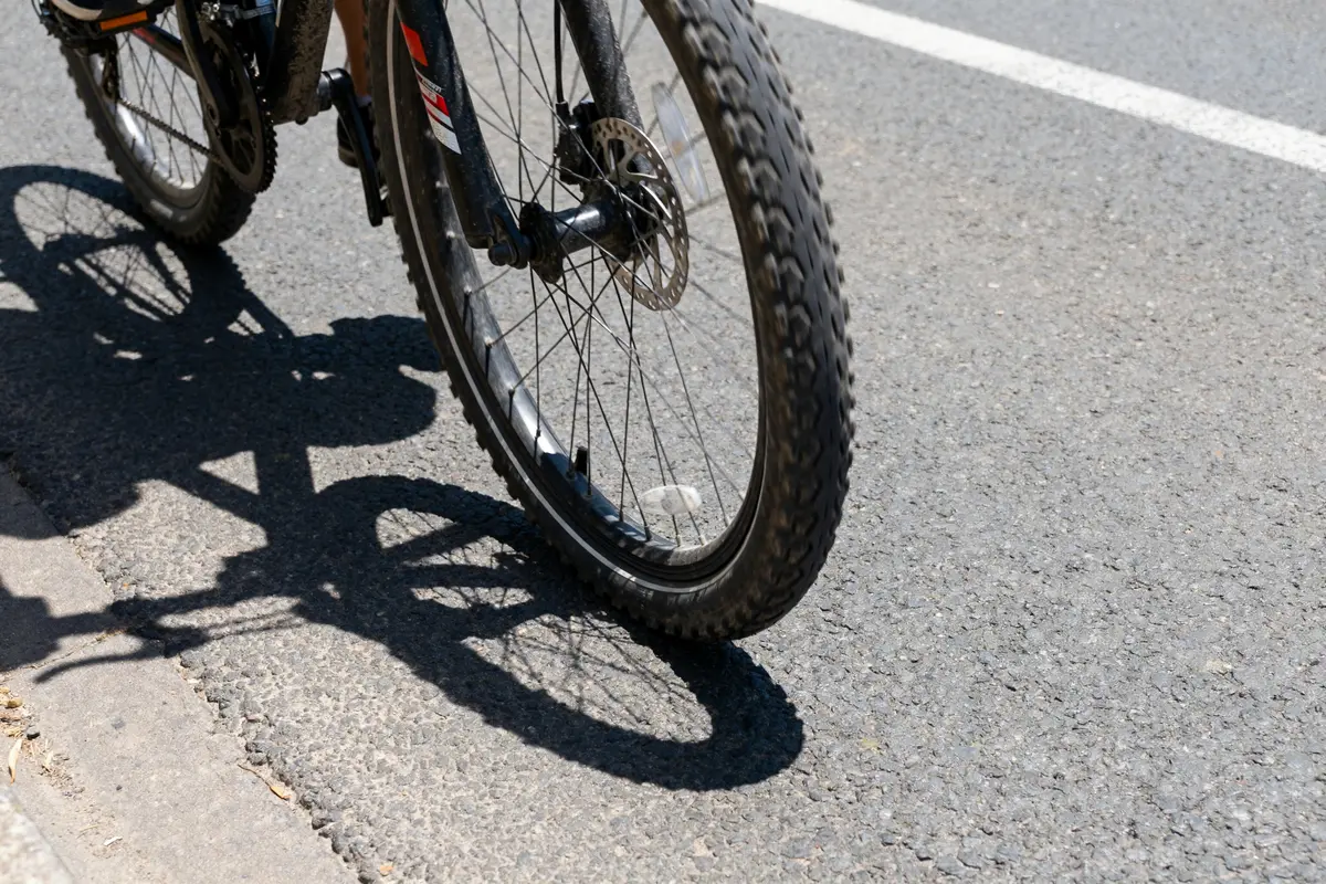 Roue de vélo sur route montrant une roue voilée en mouvement ombrée par le soleil