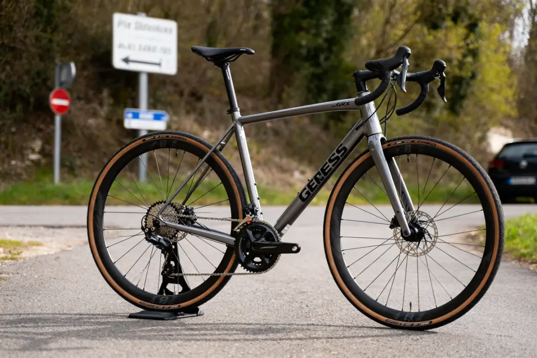 Vélo Genesis sur support, route arrière-plan avec panneaux signalétiques visibles